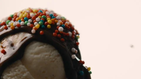 Sprinkles fall onto chocolate covered vanilla ice cream white background Stock Footage 274644648