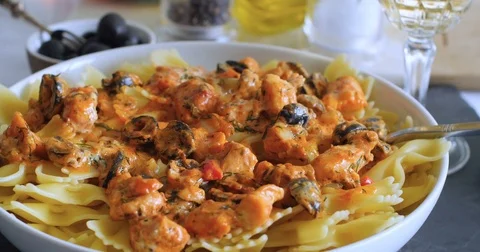 Sprinkling black pepper over pasta with fresh salmon and black olives Stock Footage 73524290