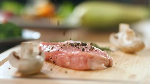 Sprinkling black pepper to raw meat piece on wooden board slow motion. 4k Dragon Stock Footage 124155188