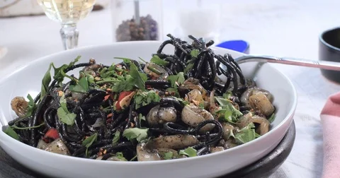 Sprinkling chilly flakes over black pasta with squids (cuttlefish) and ink Stock Footage 75277505