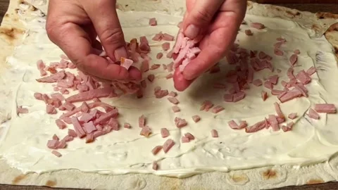 Sprinkling chopped ham on flatbread with creamy sauce for a delicious wrap snack Stock Footage 325032510