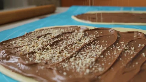 Sprinkling Chopped Nuts on Chocolate Spread Dough in Macro Detail Stock Footage 334119784