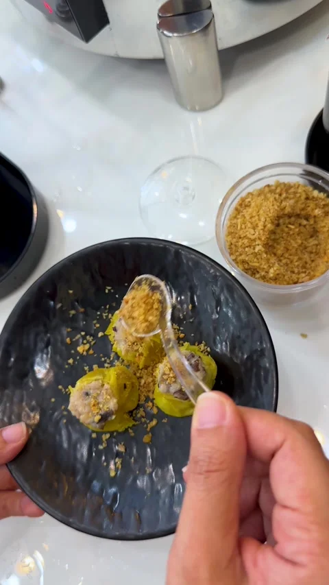 Sprinkling Fried Garlic Over Pork Shumai Dumplings on a Black Plate Stock Footage 334833412