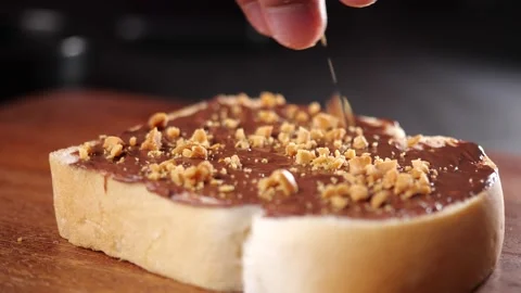 Sprinkling hazelnut on slice bread with chocolate for breakfast Stock Footage 142486096