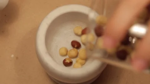 Sprinkling hazelnuts into a mortar in slow motion Stock Footage 49078942