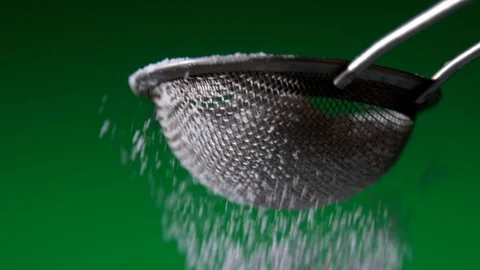Sprinkling icing powder sugar using Strainer on green background slow motion Stock Footage 122868658