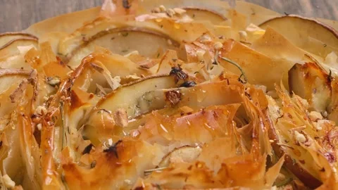 Sprinkling nuts on baked pear and cheese filo pastry pie macro view Stock Footage 327459334