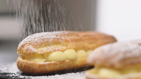 Sprinkling powdered sugar on eclair, slow motion. Video stock 154369354