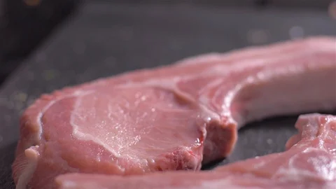 Sprinkling of raw pork chops with bone with a mix of spices Stock Footage 106471815