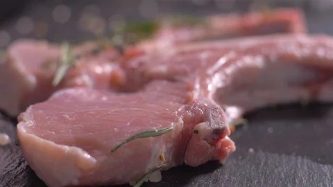 Sprinkling of raw pork chops with bone with a mix of spices Stockbeeldmateriaal 106473160