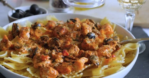 Sprinkling salt over a delicious pasta with fresh salmon and black olives Stock Footage 73132489