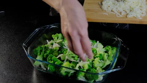 Sprinkling Shredded Cheese on Broccoli in Baking Dish at Cooking Video stock 341426304