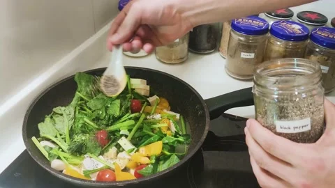 Sprinkling spices on a healthy dish cooking at home Stock Footage