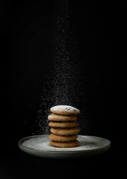 Sprinkling sugar powder stack of oatmeal cookies on a clay plate in the dark Stock Photos