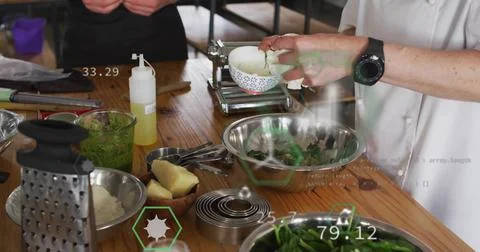 Sprinkling white-jacket chef adding herbs into greens at wooden table, bowl, 写真素材