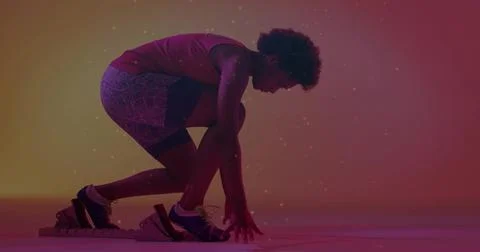 Sprinter crouching on starting block in studio, sporting tank top, patterned  Stock Photos