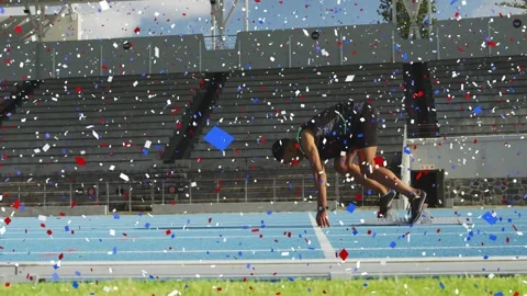 Sprinter holding set on start pushing blocks surging down blue lane confetti Stock Footage 329575648