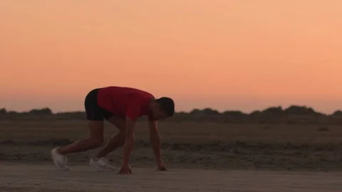 Sprinter practising start position before running in nature after sunset Stock Footage 132069778