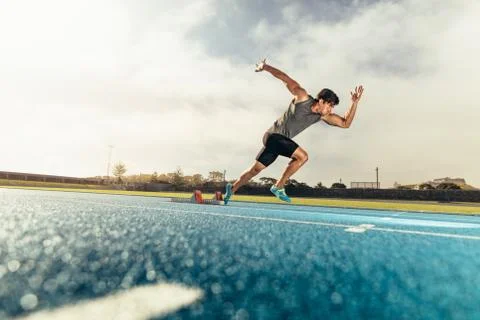 Sprinter taking off from starting block on running track Stock Photos