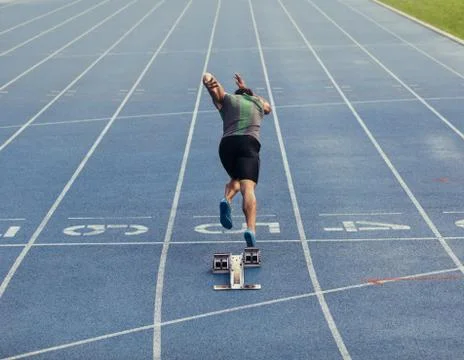 Sprinter taking off from starting block on track Stock Photos