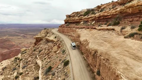 Sprinter van driving on the edge of a cliff with steep drop off in the desert Stock Footage 310348916