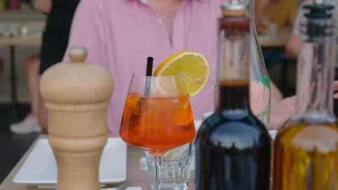A spritz cocktail on a table with a pepper mill, oil and vinegar bottles Stock Footage 344816053