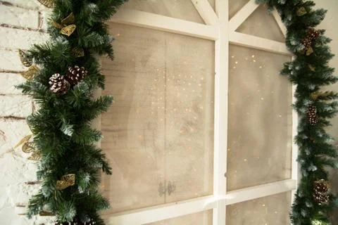 Spruce branches with cones on a background of a window frame with garlands Stock Photos