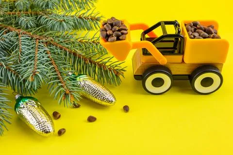 Spruce branches, cones, nuts and a toy excavator on a yellow New Year's backg Stock Photos
