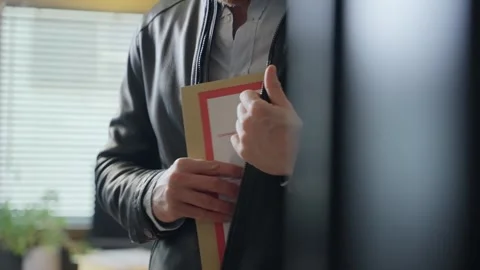 Spy agent wearing a leather jacket discreetly hides secret folder inside his Stock Footage 305211082