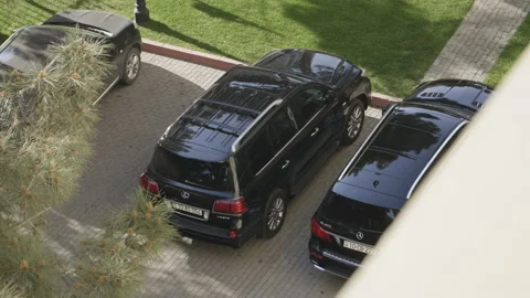 Spy view over the window at parked Lexus LX370 and Mercedes-Benz GL400 black SUV Stock Footage 160361881