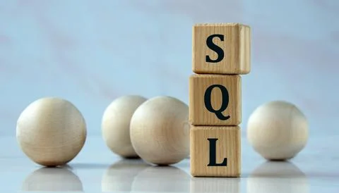 SQL - acronym on wooden cubes on the background of light balls. Stock Photos