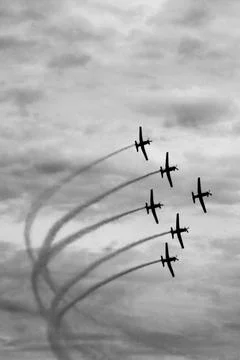 A squadron of jets leaves a dramatic trail across a cloudy sky. Stock Photos