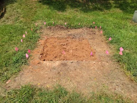 Squae plot of dirt in grass with flags for archeology Stock Photos