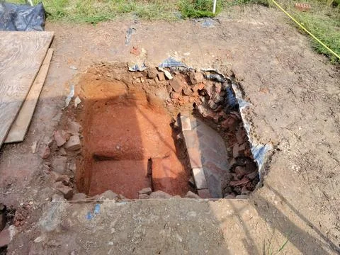 Squae plot of dirt or hole in grass with bricks for archeology Stock Photos