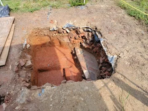 Squae plot of dirt or hole in grass with bricks for archeology Stock Photos