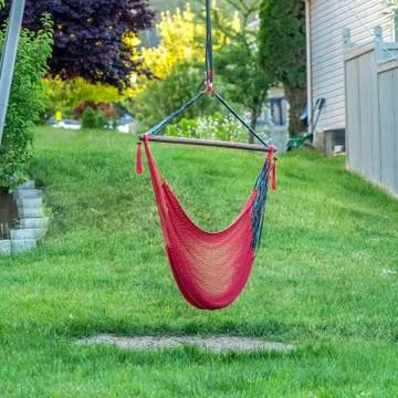 Square Backyard of home with red hammock hanging on metal pole and lush green Foto stock