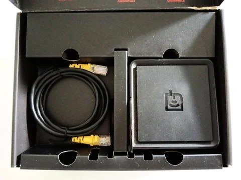 A square black networking device features two yellow Ethernet ports Stock Photos