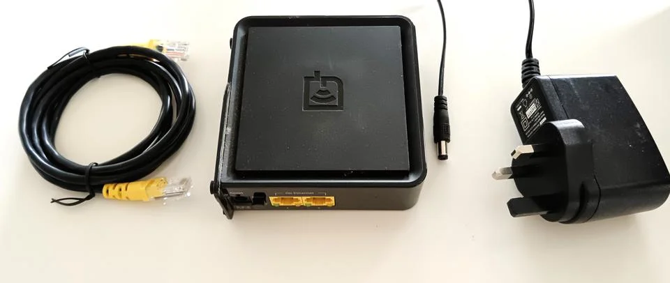 A square black networking device features two yellow Ethernet ports Stock Photos