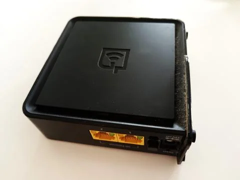 A square black networking device features two yellow Ethernet ports Stock Photos