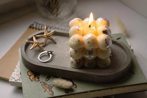 A square bubble candle is burning on a concrete stand. Stock Photos