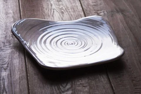 Square ceramic plate with spiral texture on rustic wooden table Stock Photos