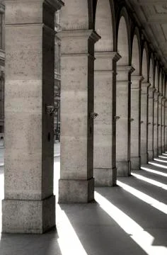 Square columns in a row with shadows cast on the ground; Paris, France Stock Photos