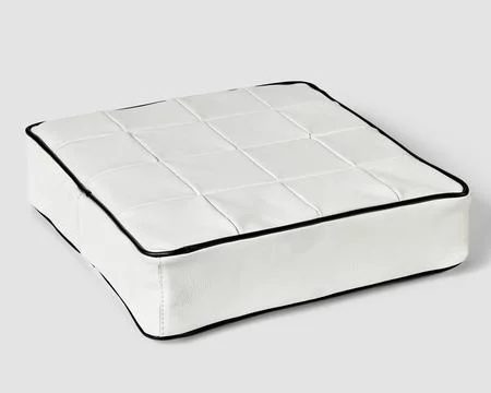 Square cushion in white patchwork leather with contrasting black trim Stock Photos