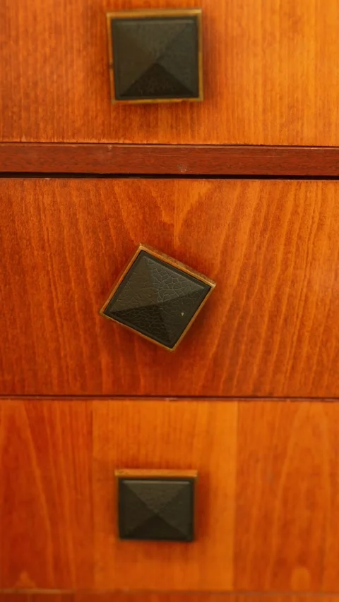 Square dark metal knobs on a wooden mid-century dresser drawer Stock-Footage 334872121