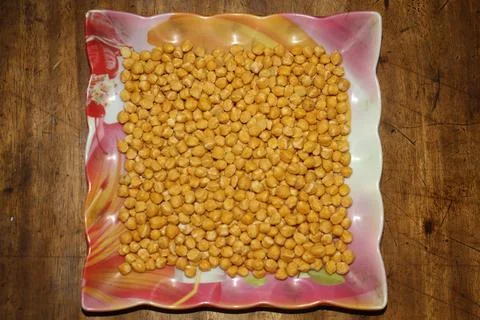 A square designed plate is containing yellow chickpeas. Stock Photos