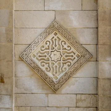 Square floral pattern unit carved into exterior stone wall of Al Hakim Mosque Stock-Fotos