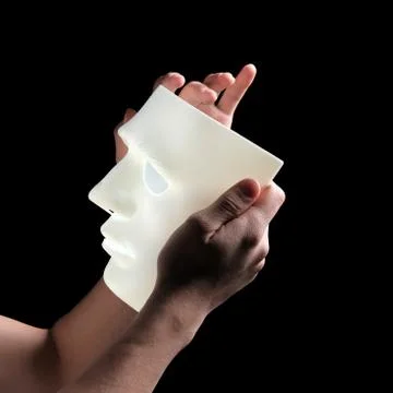 Square frame, close-up. Abstract white mask in male hands. Side view. Profile Stock Photos