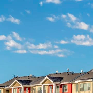 Square frame Cloudy blue sky over townhomes with cream and red wall viewed on a Stock Photos