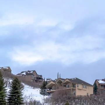 Square frame Cloudy blue sky over homes atop a hill covered with fresh white Stock Photos