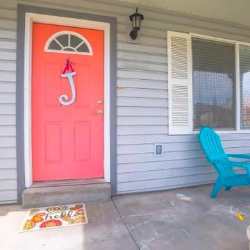 Square frame Red front door of house with blue porch chairs against windows with 스톡 사진